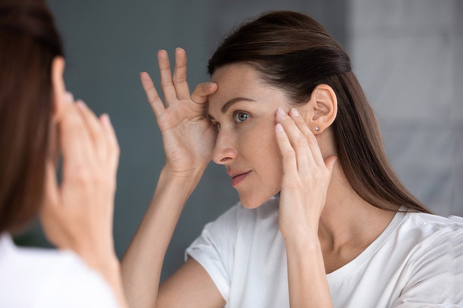 Gros plan d'une femme regardant dans un miroir vérifier le visage après le traitement de beauté à la crème de masque se sent satisfaite d'admirer la réflexion, le resurfaçage de la peau au laser, le peeling à l'acide glycolique, le concept de procédures de soins de la peau anti-âge