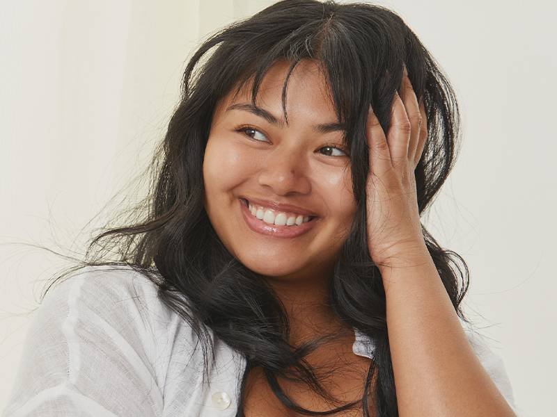 Picture of a model with bangs looking to the side and smiling