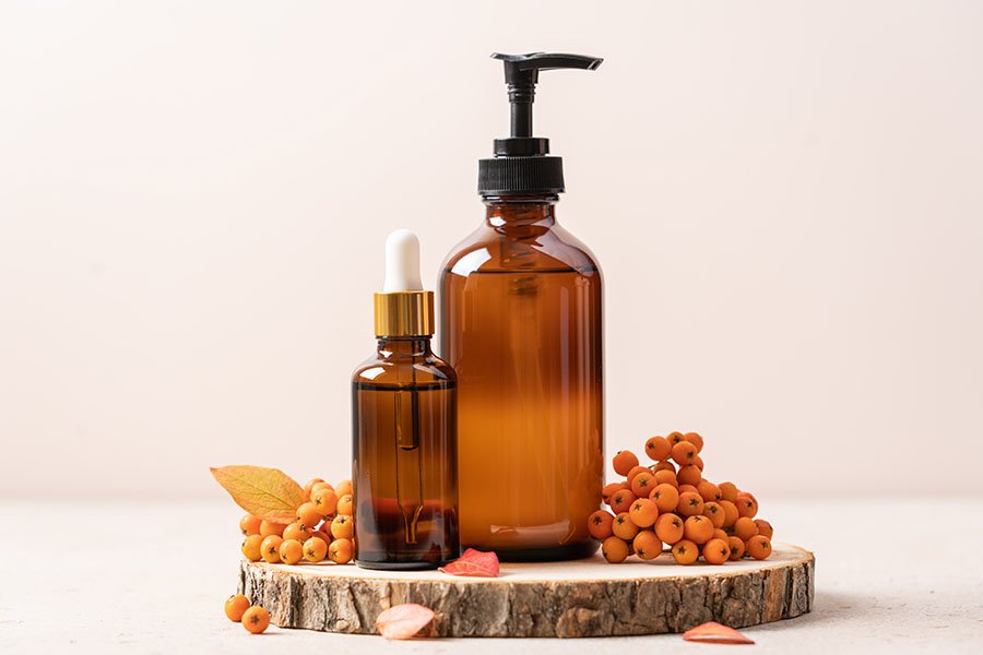 Ensemble de cosmétiques de beauté sur podium en arbre coupé à la scie avec feuilles d'automne et baies de rowan.  Concept d'automne de soins de la peau, ventes d'automne, cadeaux cosmétiques de Thanksgiving