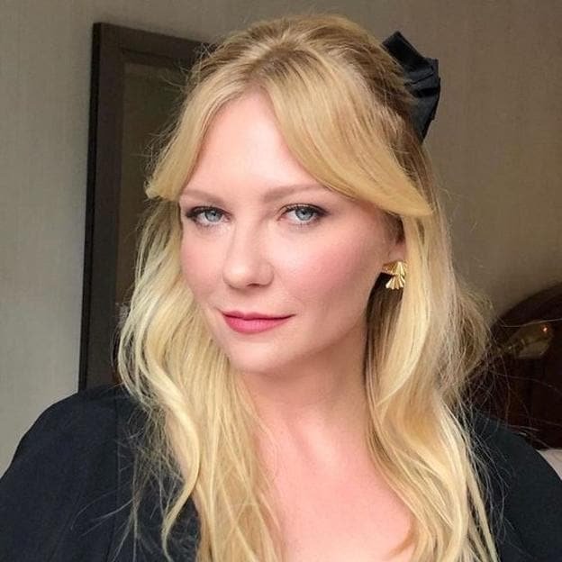 Kristen Dunst avec une coupe de cheveux bardot avec une frange en rideau pour un visage rond