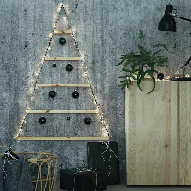 Sapin de Noël mural réalisé avec des lattes de bois et une guirlande lumineuse.