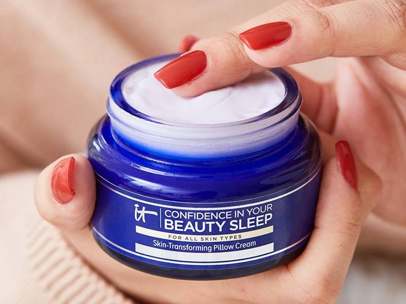 Close-up picture of a person with red nails holding the IT Cosmetics Confidence in Your Beauty Sleep Night Cream