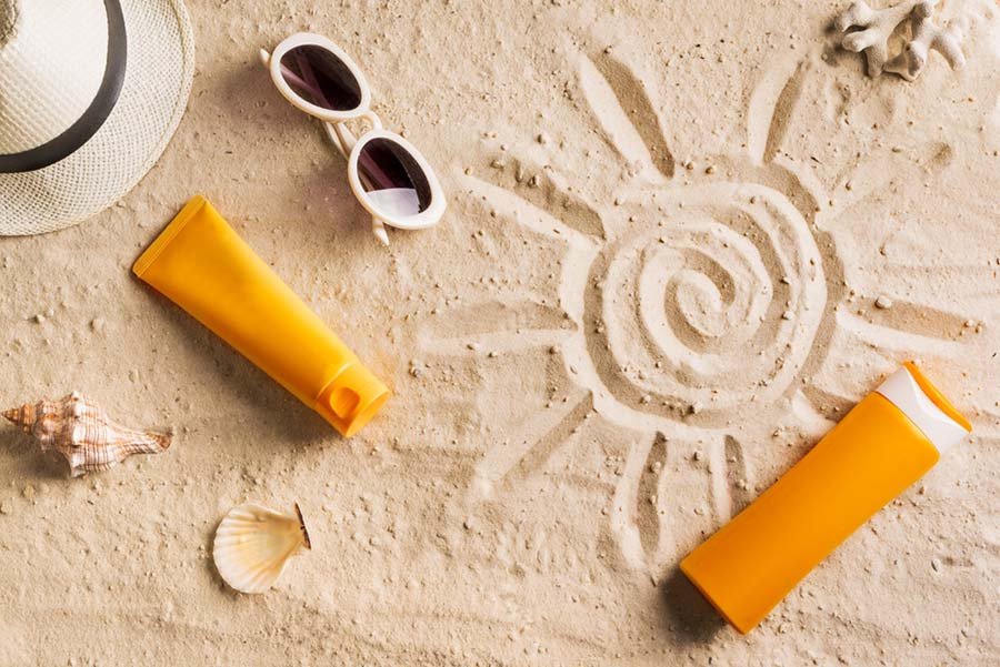 soleil dessiné dans le sable avec crème solaire