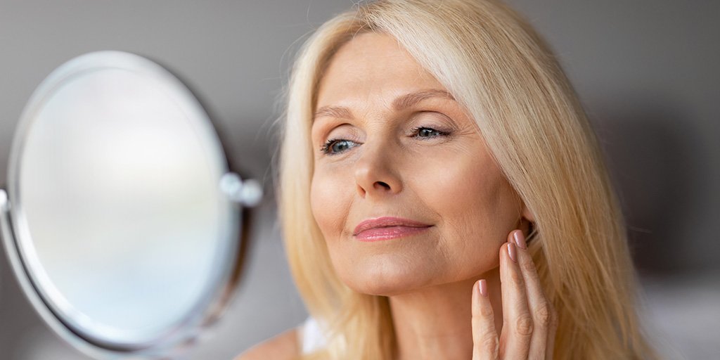 older blonde woman looking into a mirror